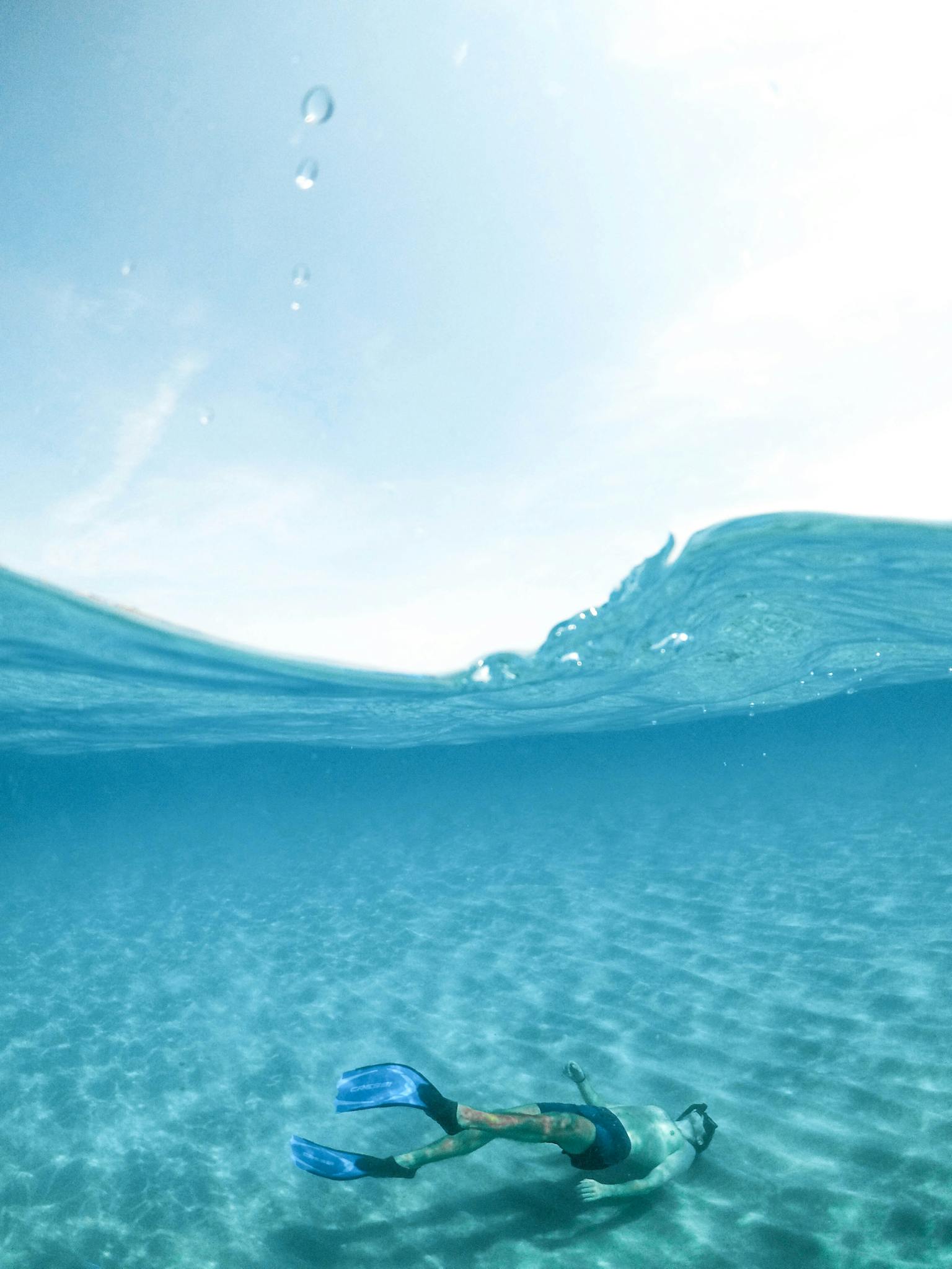 A snorkeler enjoys the crystal-clear waters of Sardinia, Italy, showcasing underwater serenity.